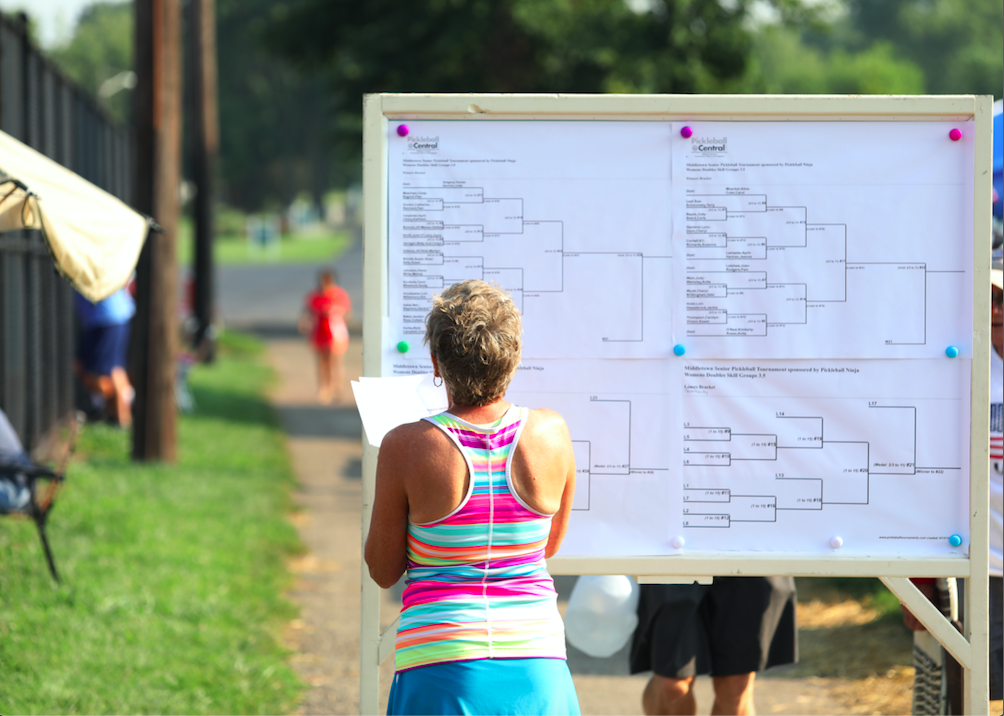 How Do Pickleball Tournaments Work. Female player looking at tournament bracket.