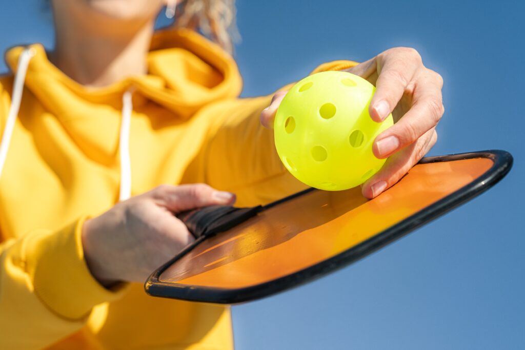 Why Pickleball is Better Than Tennis. Woman holding paddle and ball.